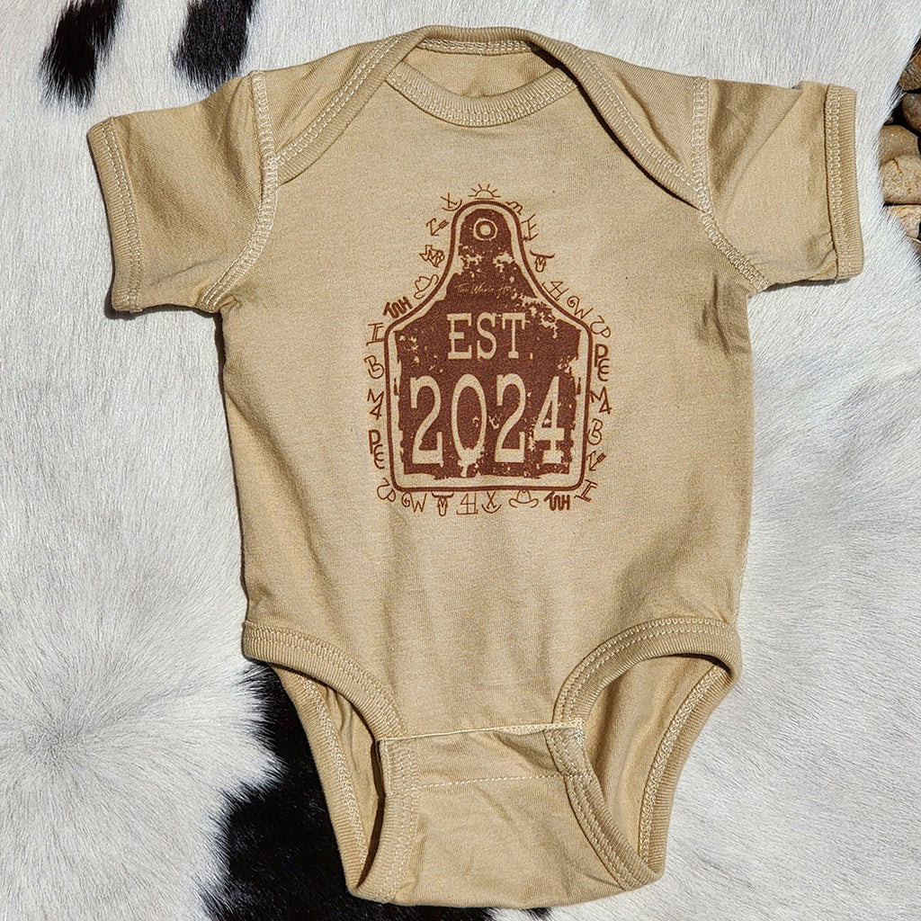 tan onesie with ear tag picture that has 2024 in it 