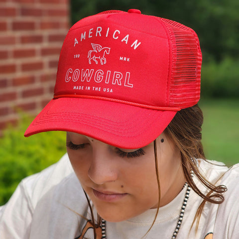 red trucker cap with American Cowgirl written on the front. 
