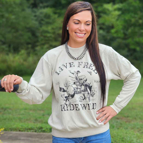 Oat Colored sweatshirt with bronc rider and Live free wild wild saying 