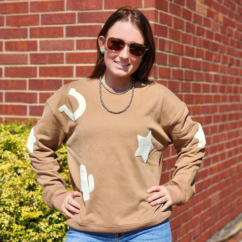 tan sweat shirt with large patches of horseshoes, cactus and stars. 